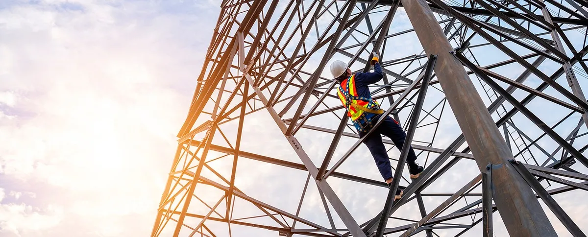 Técnico asegurado trabajando en una torre metálica
